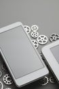 Modern smartphone and small gears on gray table Royalty Free Stock Photo
