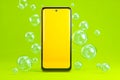 Modern smartphone with vibrant display surrounded by floating bubbles against lime green background Royalty Free Stock Photo
