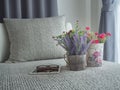 modern sofa with purple lavender flower and rose flower on flowerpot and eyeglasses on tablet at bedroom.