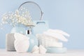 Modern soft light interior for bathroom - pastel blue ceramic bowls, flowers, mirror, silver cosmetic accessories on white wood.