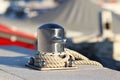 A modern stainless steel bollard with mooring on the dock in the harbor against the background of yachts on a sunny day. Outfittin Royalty Free Stock Photo