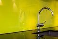 Modern stainless steel faucet and sink near poisen green wall, retro design
