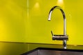 Modern stainless steel faucet and sink near poisen green wall, retro design