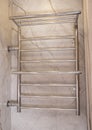 Modern stainless steel water heated towel rail hanging on the wall in the bathroom, close-up Royalty Free Stock Photo