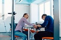 In a modern startup office, a businessman and a businesswoman business colleagues engage in a symbolic arm-wrestling