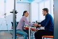 In a modern startup office, a businessman and a businesswoman business colleagues engage in a symbolic arm-wrestling