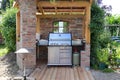 Modern steel gas grill in a shelter made of old bricks and wood, concept for barbecue and garden design