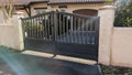 Modern steel grey gate aluminum portal with blades in sunny flare day suburbs house street