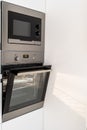 Modern steel microwave and opened oven in kitchen