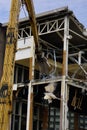 A modern steel structure building being demolished by a machine Royalty Free Stock Photo
