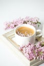 Modern still life with lilac flowers, frame and cup of coffee, on white wbackground, copy space. Holiday or wedding background.