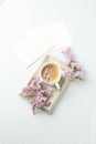 Modern still life with lilac flowers, frame and cup of coffee, on white wbackground, copy space. Holiday or wedding background.