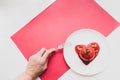 Modern still life scene. Fork in a female hand, tomato in heart shape tomato paste on a white plate.