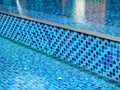Modern style of blue tone mosaic decoration on the wall and floor of outdoor swimming pool background. Royalty Free Stock Photo