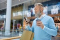 Modern stylish aged man with shopping bags texting message on phone Royalty Free Stock Photo