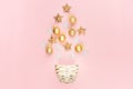 Modern stylish gold christmas tree shape of sparkling decorations - balls, stars on soft light pastel pink background, top view. Royalty Free Stock Photo