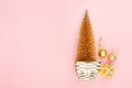 Modern stylish gold christmas tree with sparkling decorations, gift on soft light pastel pink background, top view, copy space. Royalty Free Stock Photo