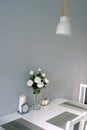 Modern stylish interior of dining room in soft pastel colors with white rose bouquet in vase on the table Royalty Free Stock Photo