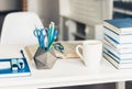 Modern stylish office work place with open book, glasses, office supplies and books, desk work concept in white and blue colors Royalty Free Stock Photo