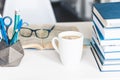 Modern stylish office work place with open book, glasses, office supplies and books, desk work concept in white and blue colors