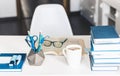 Modern stylish office work place with open book, glasses, office supplies and books, desk work concept in white and blue colors