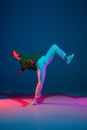 Stylish sportive boy dancing hip-hop in stylish clothes on colorful background at dance hall in neon light. Youth Royalty Free Stock Photo