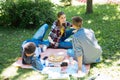 Modern stylish students sitting on the grass while having picnic Royalty Free Stock Photo