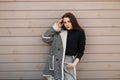 Modern stylish young brunette woman in a gray vintage pants in a black T-shirt in a trendy plaid jacket in retro style Royalty Free Stock Photo