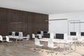 Modern sunny open space office with eco style interior: white tables and chairs, wooden floor and dark brown wall Royalty Free Stock Photo