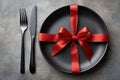 Modern table setting featuring a black plate adorned with a red ribbon Royalty Free Stock Photo