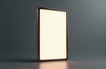 Modern tablet with blank bright screen stands vertically on reflective surface. Sleek portable digital device on dark grey Royalty Free Stock Photo