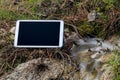 Modern tablet computer placed beside river outdoors. Royalty Free Stock Photo