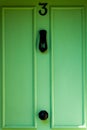 Dark green wooden front door with the house number 3
