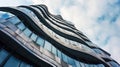 Modern tall building with futuristic design, low angle view of abstract curve shapes and sky. Wavy geometric facade with glass and Royalty Free Stock Photo