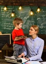 Modern teacher hipster writing on big blackboard with math formula, Tutor sitting beside desk during private lessons at Royalty Free Stock Photo