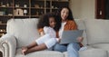 African mom her daughter sit on sofa use laptop