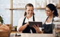 Modern tech makes them a more productive team. two women using a digital tablet together while working in a cafe. Royalty Free Stock Photo
