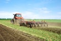 Modern tech red tractor plowing a green agricultural field in spring on the farm. Harvester sowing wheat. Royalty Free Stock Photo