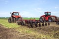 Modern tech red tractor plowing a green agricultural field in spring on the farm. Harvester sowing wheat. Royalty Free Stock Photo