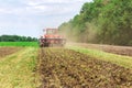 Modern tech red tractor plowing a green agricultural field in spring on the farm. Harvester sowing wheat. Royalty Free Stock Photo