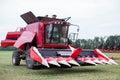 Modern tech red tractor plowing a green agricultural field in spring on the farm. Harvester sowing wheat. Royalty Free Stock Photo