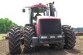 Modern tech red tractor plowing a green agricultural field in spring on the farm. Harvester sowing wheat. Royalty Free Stock Photo