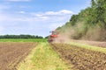 Modern tech red tractor plowing a green agricultural field in spring on the farm. Harvester sowing wheat. Royalty Free Stock Photo