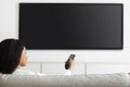 Modern technologies. Black woman watching TV pointing remote control at flatscreen television set with black screen Royalty Free Stock Photo