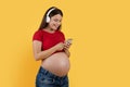 Modern Technologies. Happy Pregnant Woman In Wireless Headphones Listening Music On Smartphone Royalty Free Stock Photo