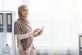 Smiling Islamic Businesswoman Using Digital Tablet, Posing Near Window Indoors