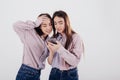 Modern technology. Two sisters twins standing and posing in the studio with white background Royalty Free Stock Photo