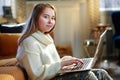 Modern teen girl with laptop sitting near couch Royalty Free Stock Photo