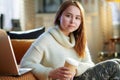 Modern teenage girl with cup of hot beverage and laptop Royalty Free Stock Photo