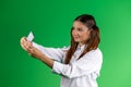 Modern teenage girl in school clothes, taking a selfie on a mobile phone. Green background Royalty Free Stock Photo